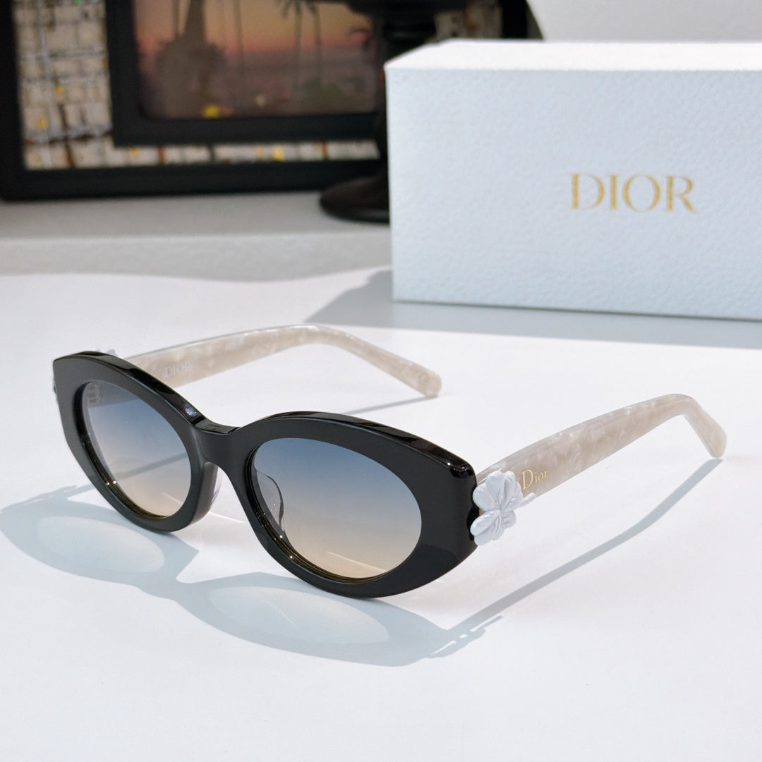 Black Dior sunglasses with round lenses and clear arms, white floral bow detail.