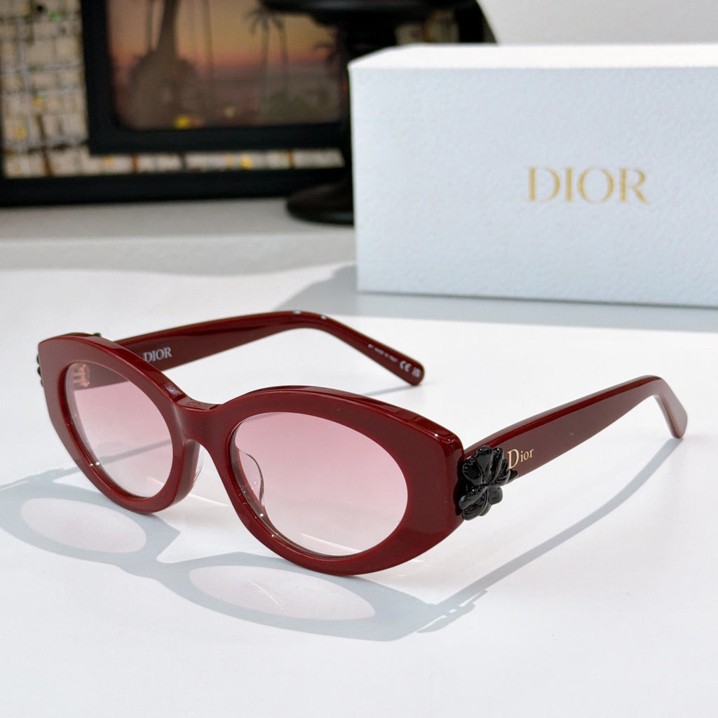 Red Dior sunglasses with round lenses and black floral accent on the temple.