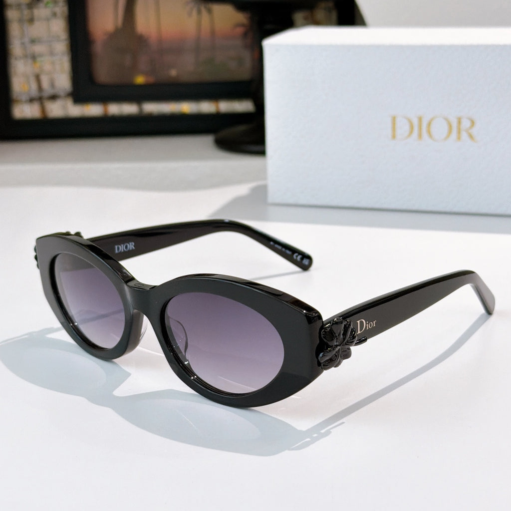 Black Dior sunglasses with oval lenses and purple tint, white floral detail on temple.