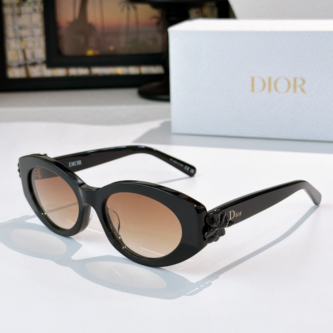 Black Dior sunglasses with oval lenses and white floral bow detail on the arm.