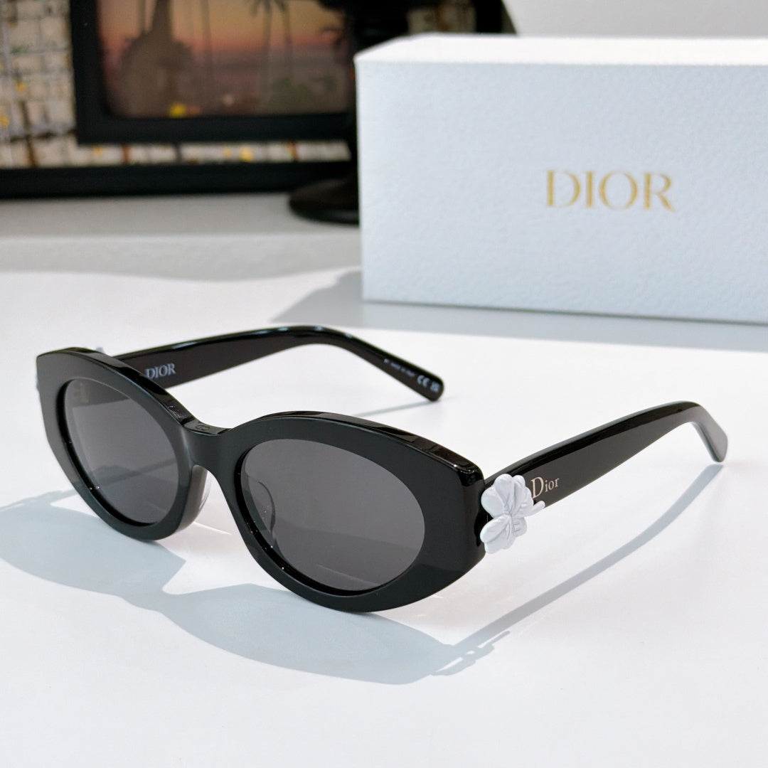 Black Dior sunglasses with oval lenses and white floral detail on the temple.