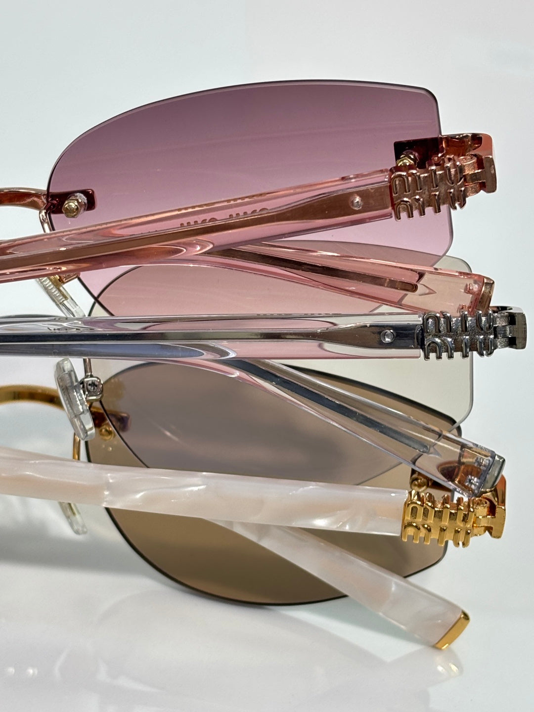 MiuMiu glasses close-up: rose-tinted lenses with gold metal hinge and frame detail