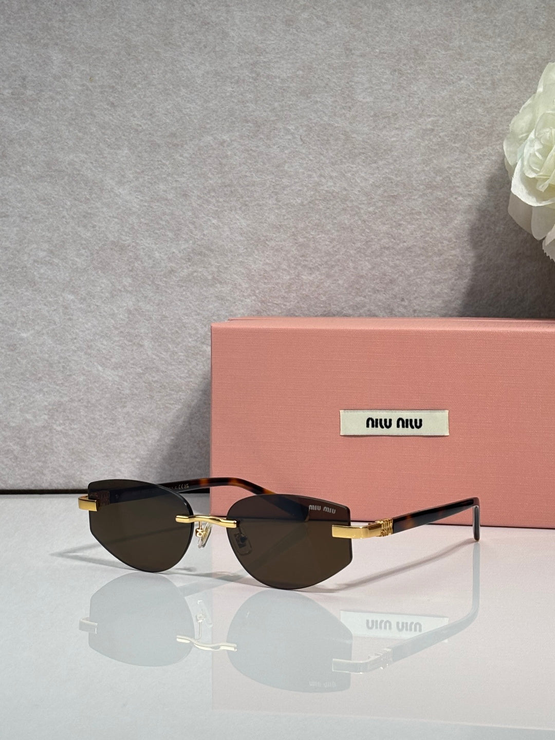 MiuMiu glasses with dark tinted lenses and slim metal frame with gold details