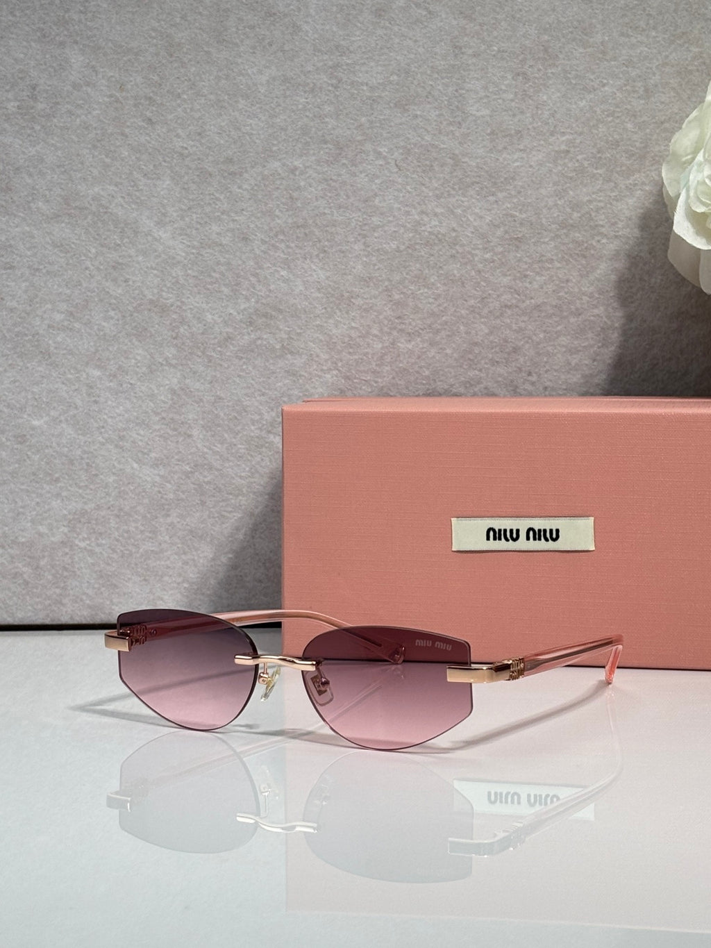 MiuMiu glasses with rose-tinted lenses and thin metal frame, gold temple accents
