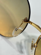 Close-up of gold sunglasses frame with clear temple tip and lens edge.