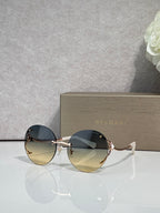 Gold-rim round sunglasses with dark blue gradient lenses and curved metal temples.
