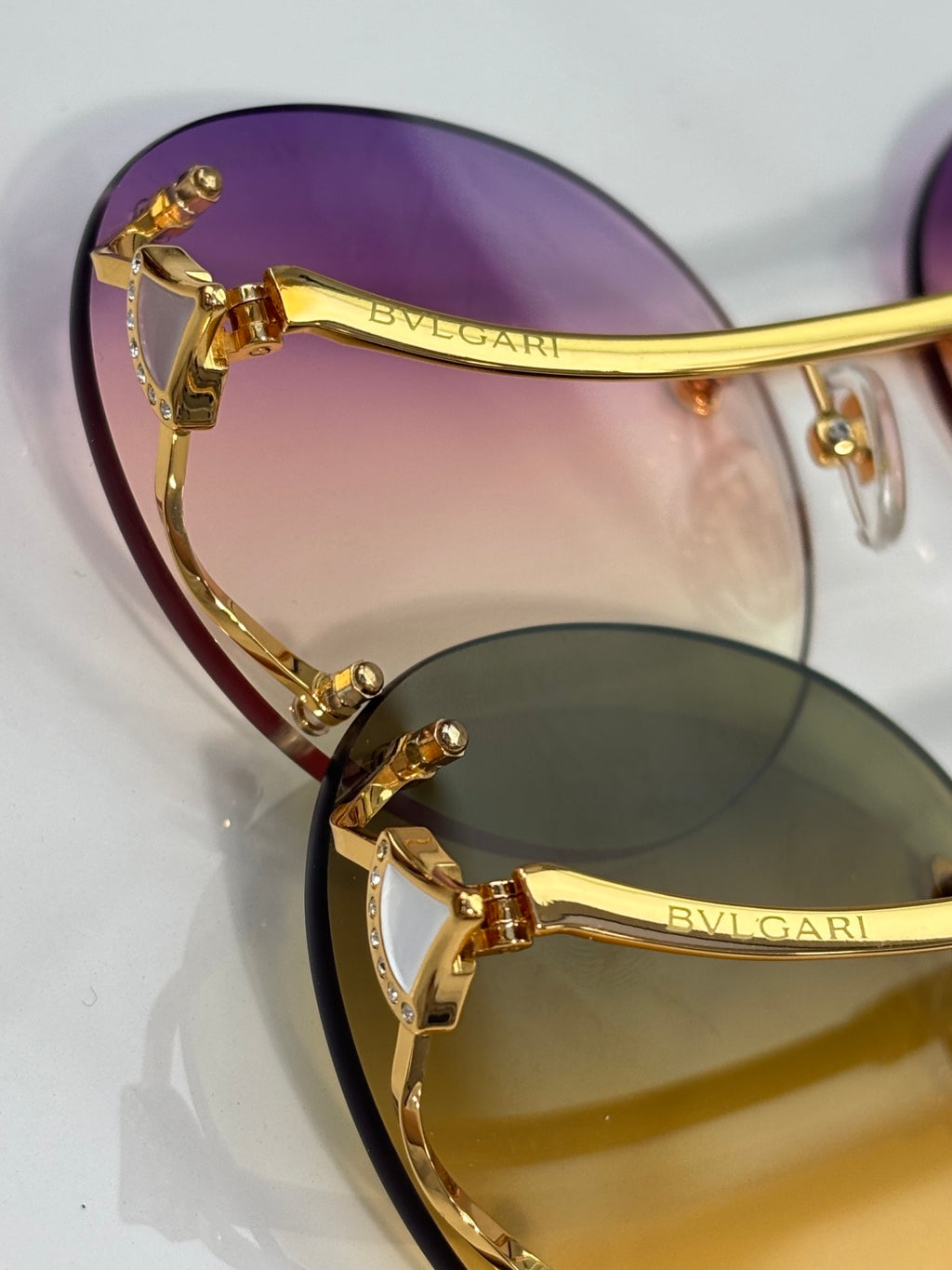 Close-up of gold sunglasses frame with purple lens and bridge detail.