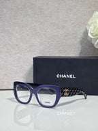 Eyeglasses with blue frames and patterned temple, featuring a gold Chanel logo.