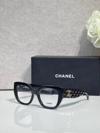 Eyeglasses with black frames and patterned temple, featuring a gold Chanel logo.