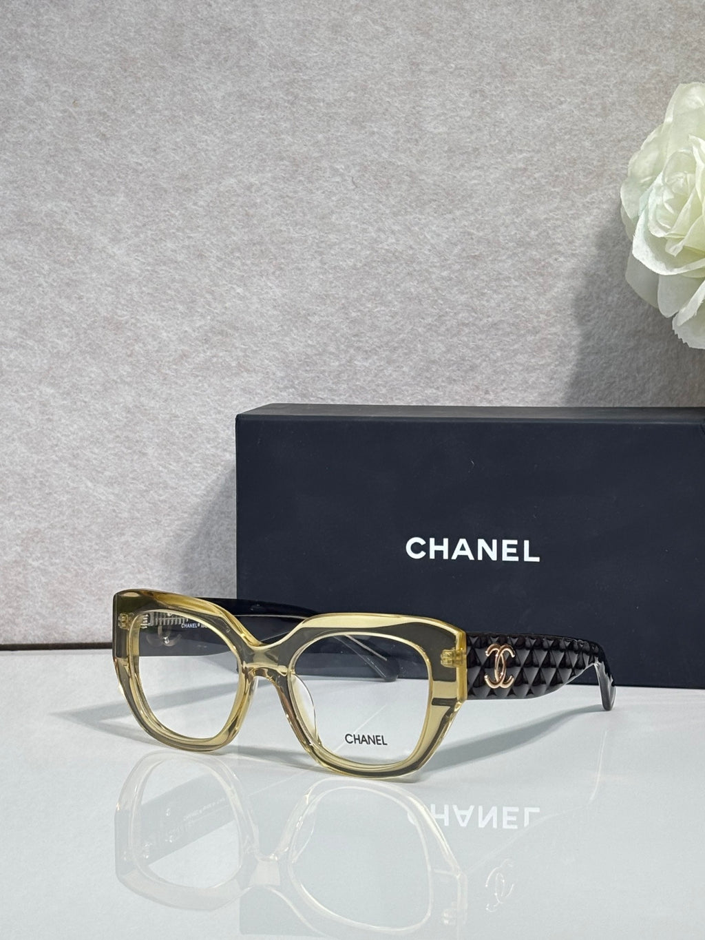 Eyeglasses with gold frames and patterned temple, featuring a gold Chanel logo.