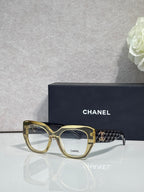 Eyeglasses with gold frames and patterned temple, featuring a gold Chanel logo.