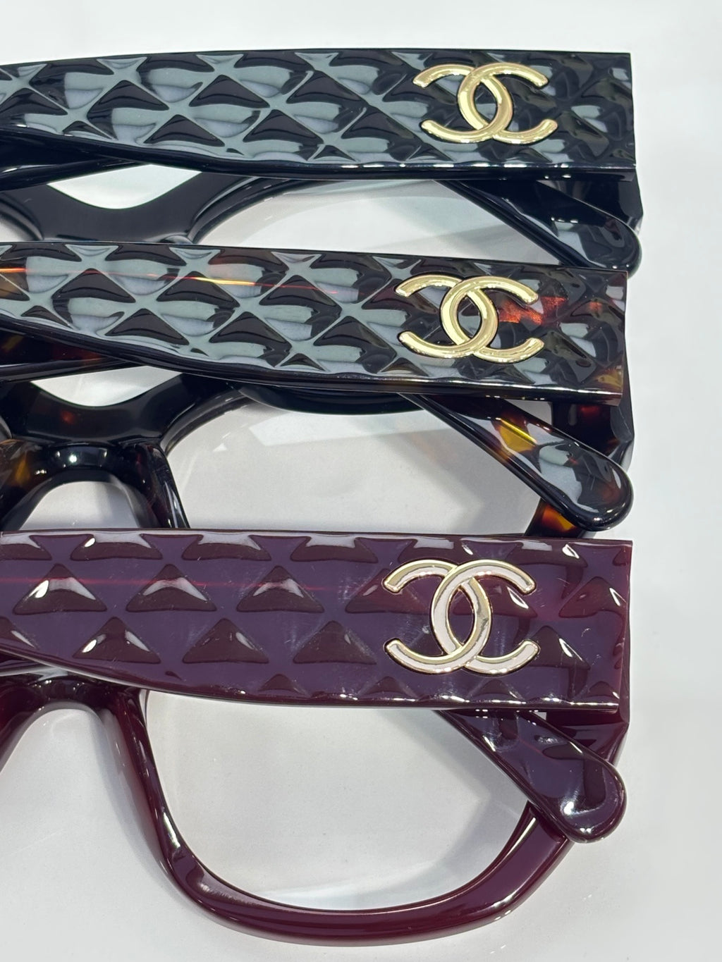Eyeglasses set: patterned black and maroon frames with gold Chanel logo on temples.