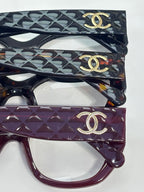 Eyeglasses set: patterned black and maroon frames with gold Chanel logo on temples.