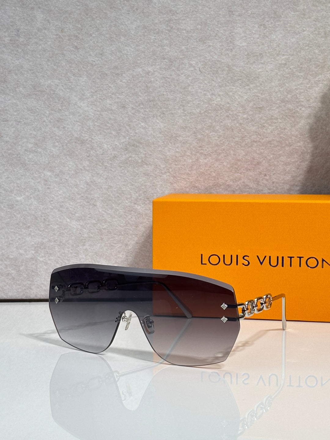 Louis Vuitton sunglasses with dark gradient lenses and gold chain side bar