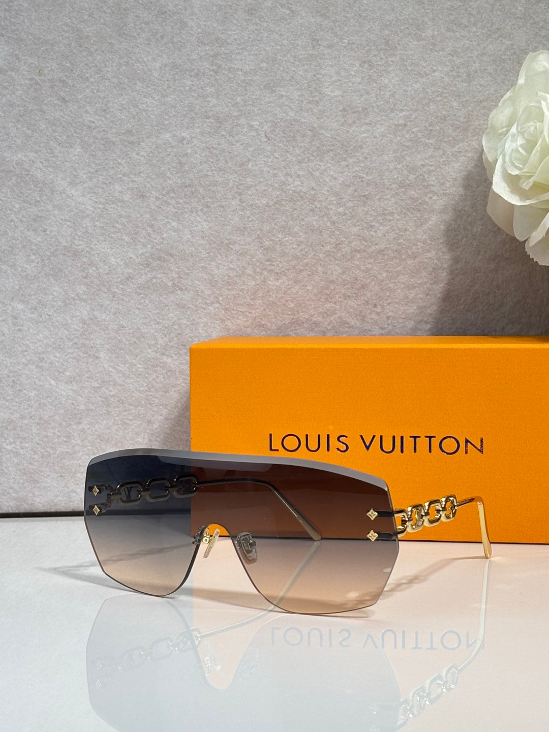 Louis Vuitton sunglasses with dark gradient lenses and gold chain link detail