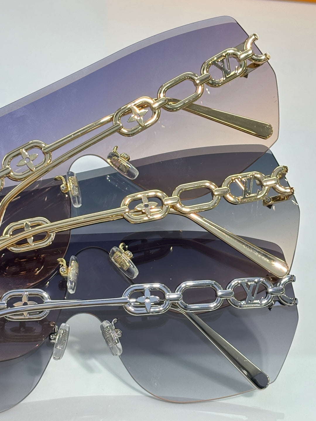 Louis Vuitton sunglasses close-up with gold chain bar over dark lenses