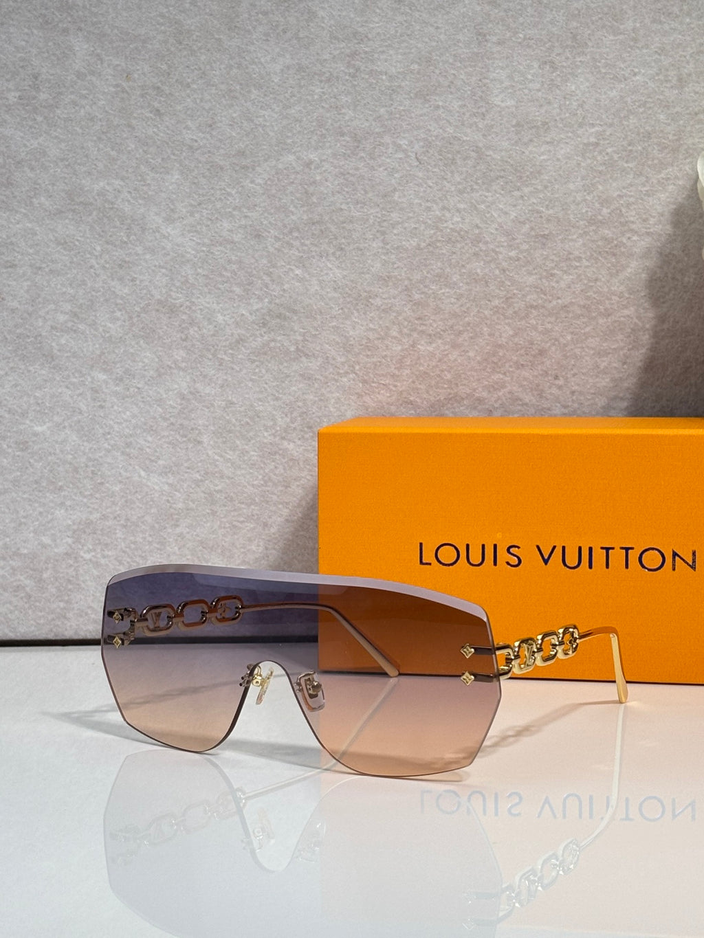 Louis Vuitton sunglasses with amber-brown gradient lenses and gold chain detail