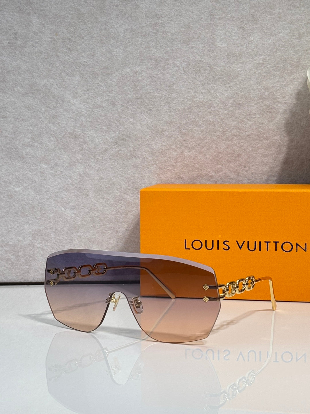 Louis Vuitton sunglasses with amber-brown gradient lenses and gold chain detail
