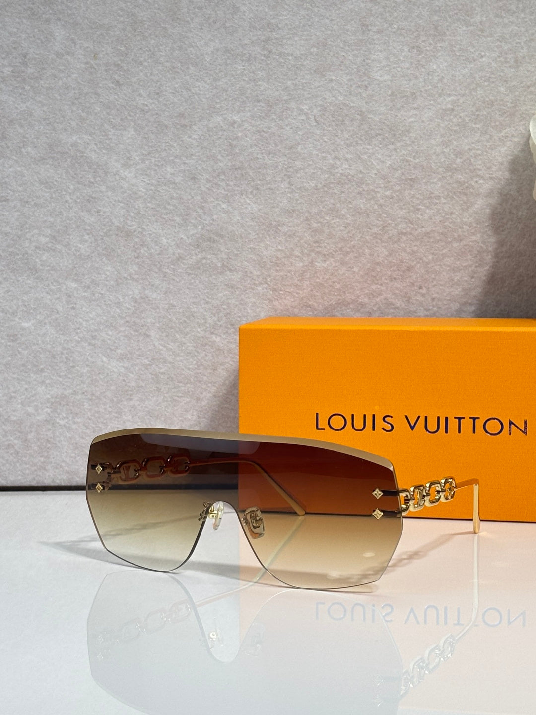 Louis Vuitton sunglasses with amber gradient lenses and brown frame, gold chain detail