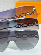 Louis Vuitton sunglasses close-up with gold chain motif over gradient lenses