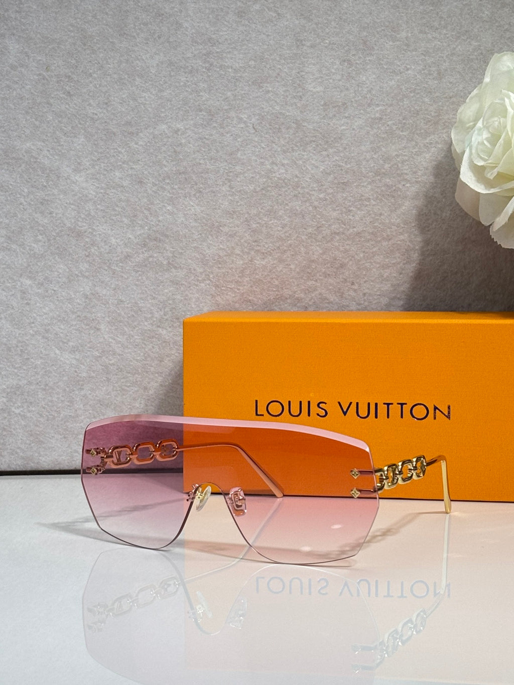 Louis Vuitton sunglasses with rose gradient lenses and dark frame with gold chain detail