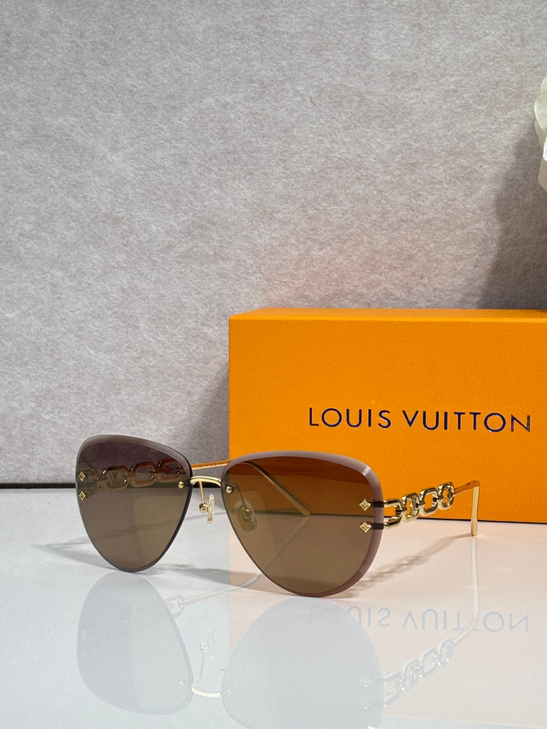 Louis Vuitton sunglasses with brown tinted lenses and gold chain temple detail