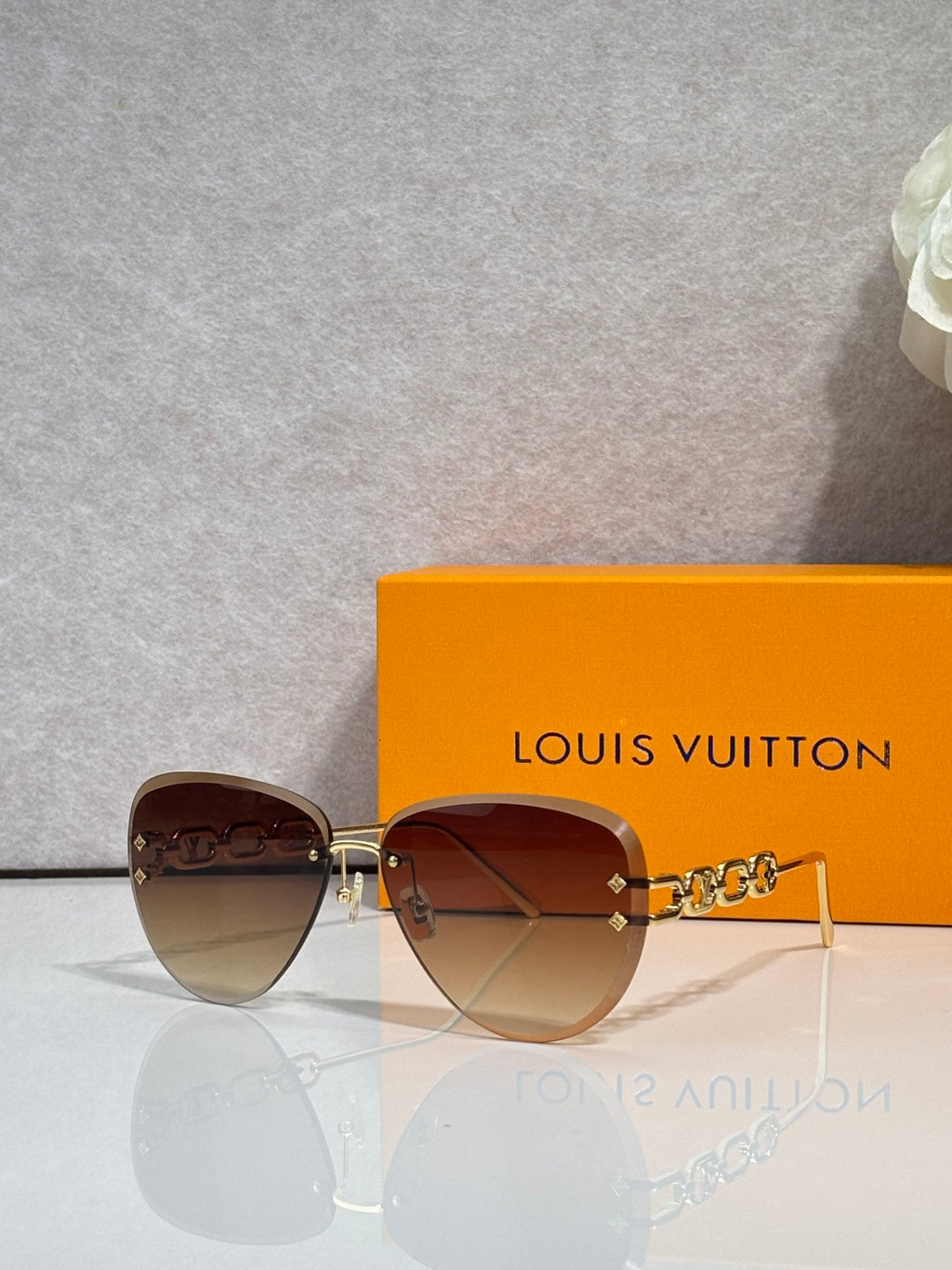 Louis Vuitton sunglasses with darker gradient lenses, gold chain-style temple detail