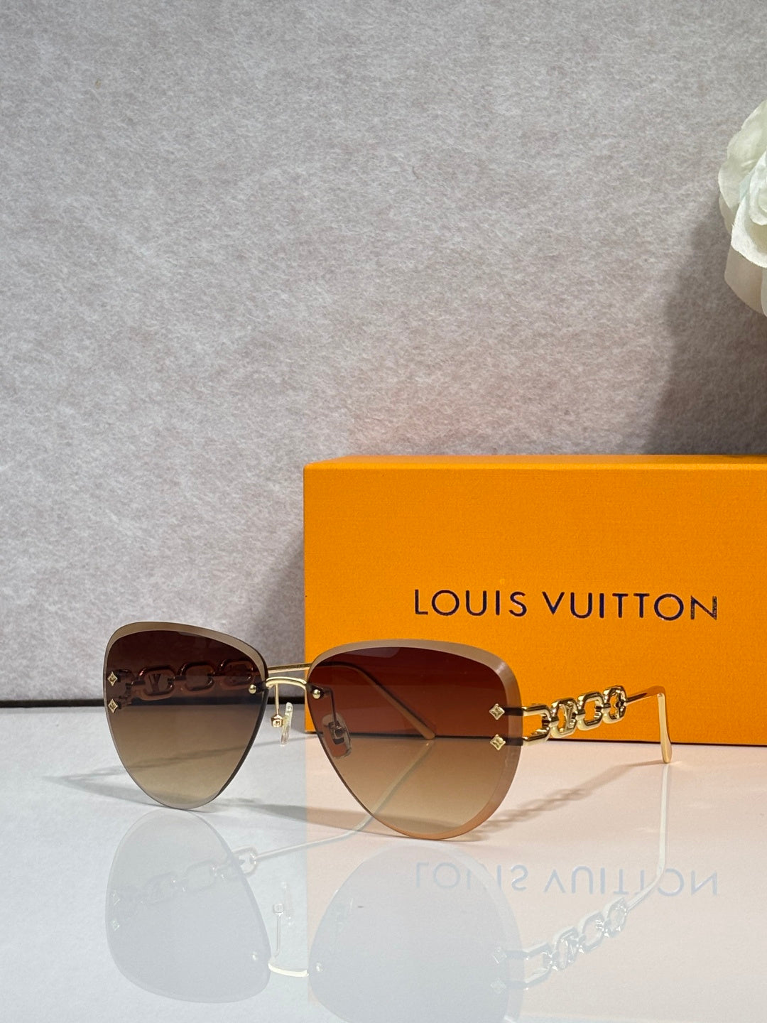Louis Vuitton sunglasses with darker gradient lenses, gold chain-style temple detail
