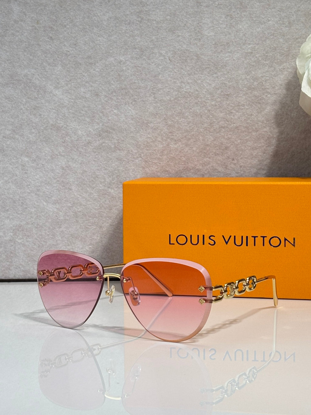Louis Vuitton sunglasses with pink-to-amber tinted lenses, gold frame and chain temples