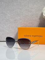 Louis Vuitton sunglasses with dark tinted lenses and gold chain temple links