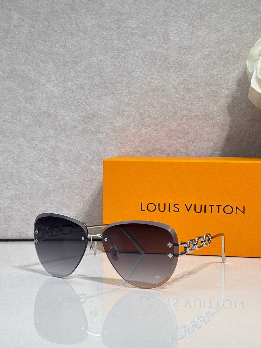Louis Vuitton sunglasses with dark tinted lenses and gold chain temple links