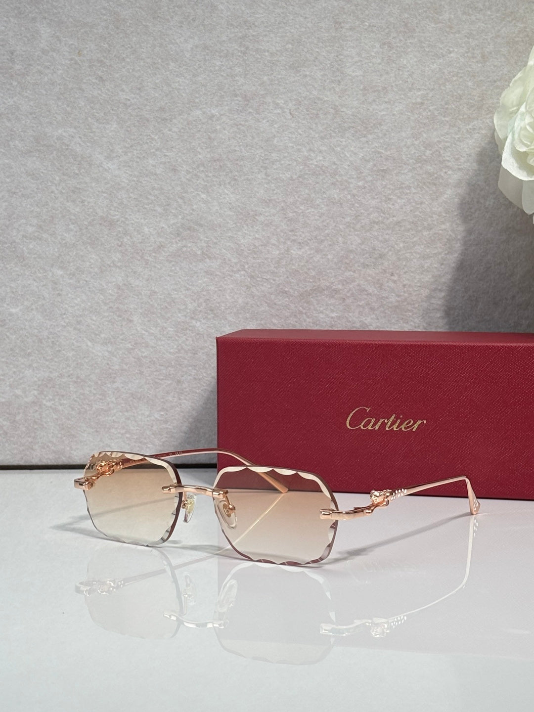 Cartier eyeglasses with gold-tone metal frame and rose-tinted lenses, angled view.