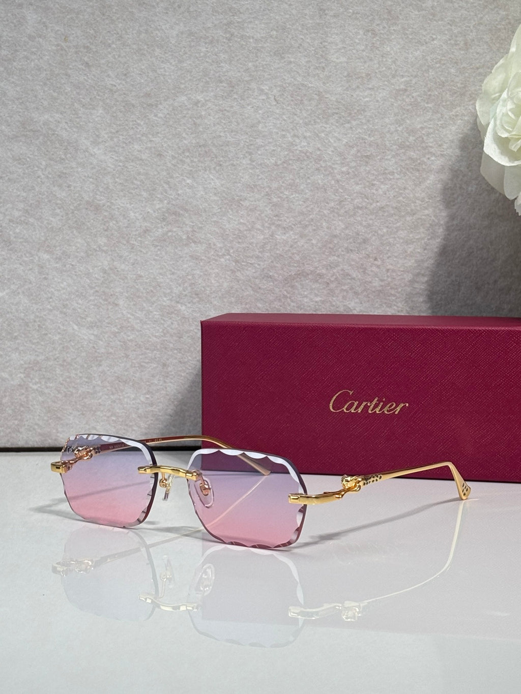 Cartier eyeglasses with gold-tone metal frame and pink gradient lenses, front view.