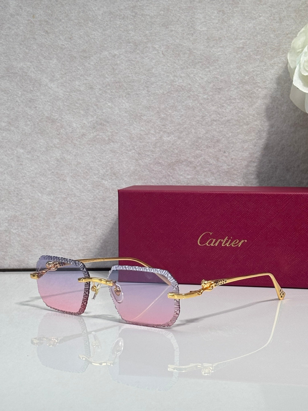 Gold-tone eyeglasses with light pink tinted lenses and decorative temple detailing.