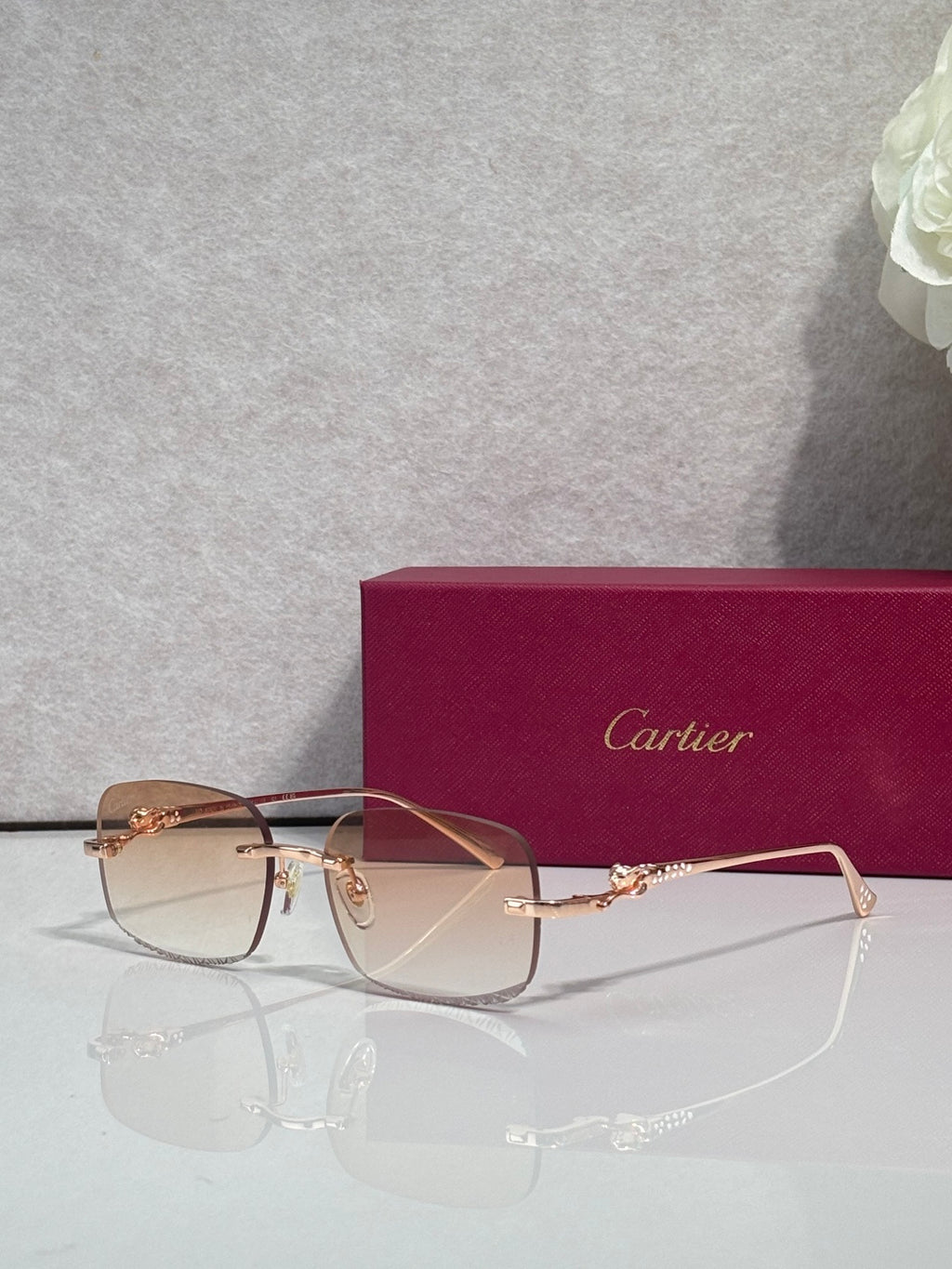 Cartier eyeglasses with gold-tone metal frame and tinted lenses, front view on stand
