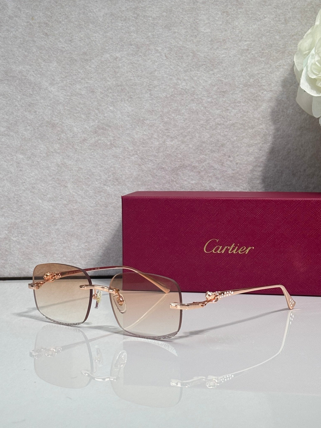 Cartier eyeglasses with gold-tone metal frame and tinted lenses, front view on stand