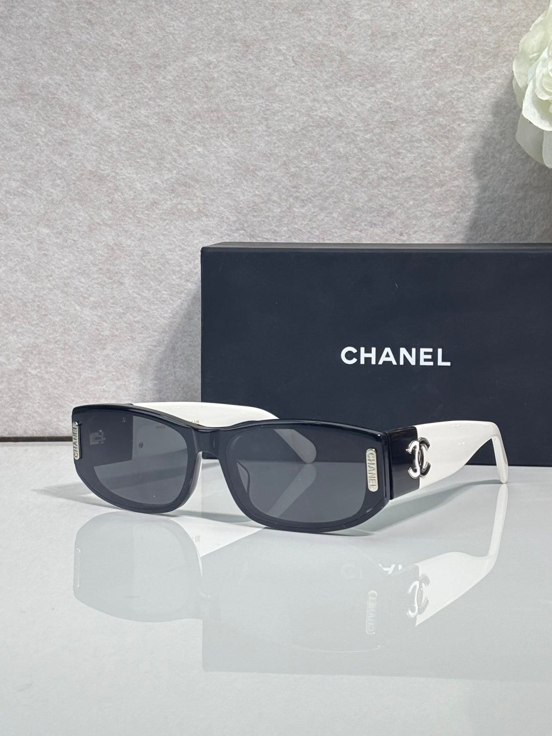 Chanel sunglasses with dark frames and white arms, rectangular lenses