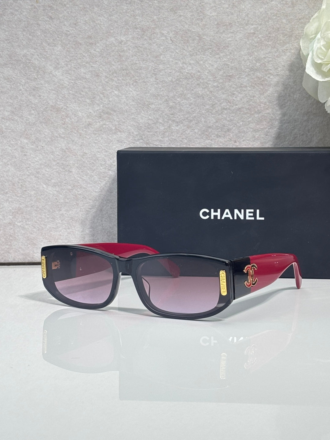 Chanel sunglasses with dark frames, pink and red-toned arms, rectangular lenses