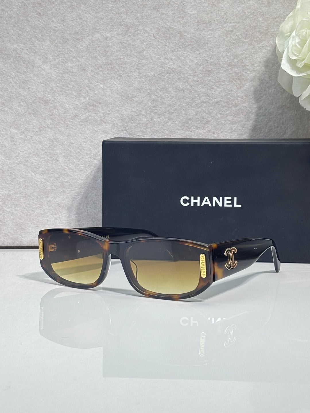 Chanel sunglasses with dark frames, tan arms, rectangular lenses