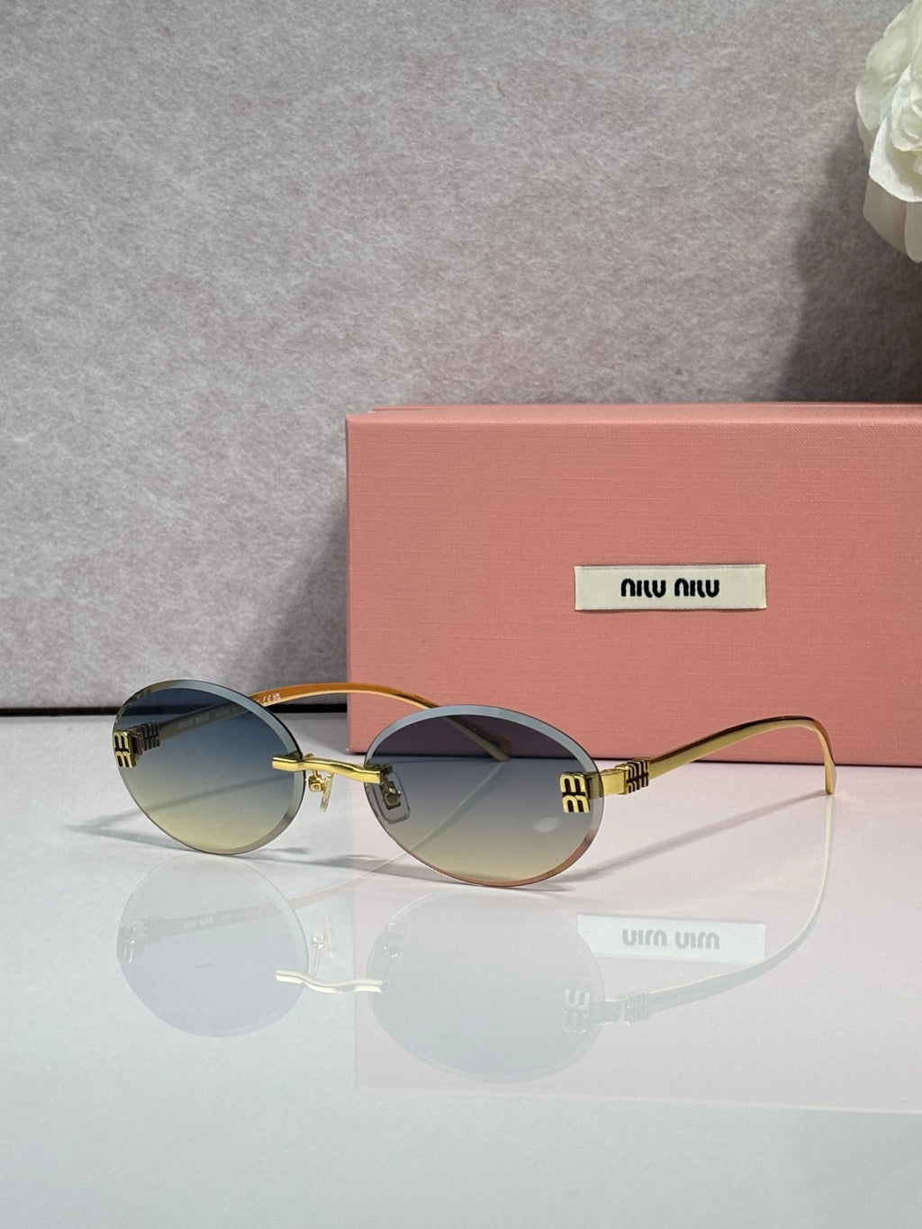MiuMiu round sunglasses with tinted lenses, gold-toned metal frame, logo on temple arms