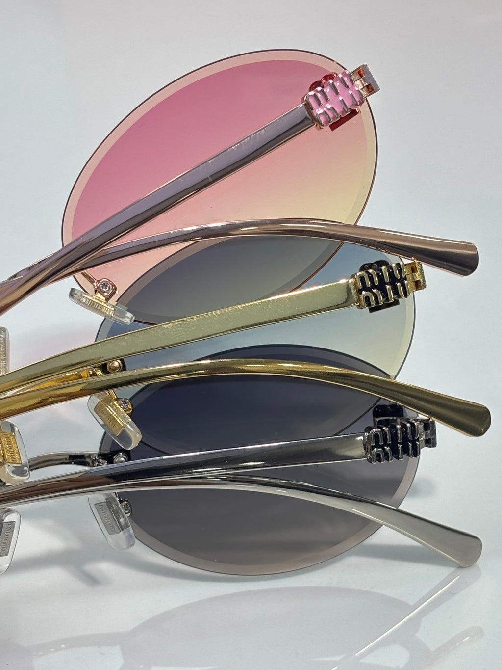 MiuMiu round sunglasses shown from side, pink gradient lenses, gold-toned metal arms