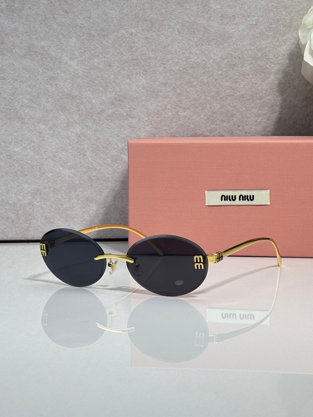 MiuMiu round sunglasses with dark lenses, gold-toned frame, logo on temple arms