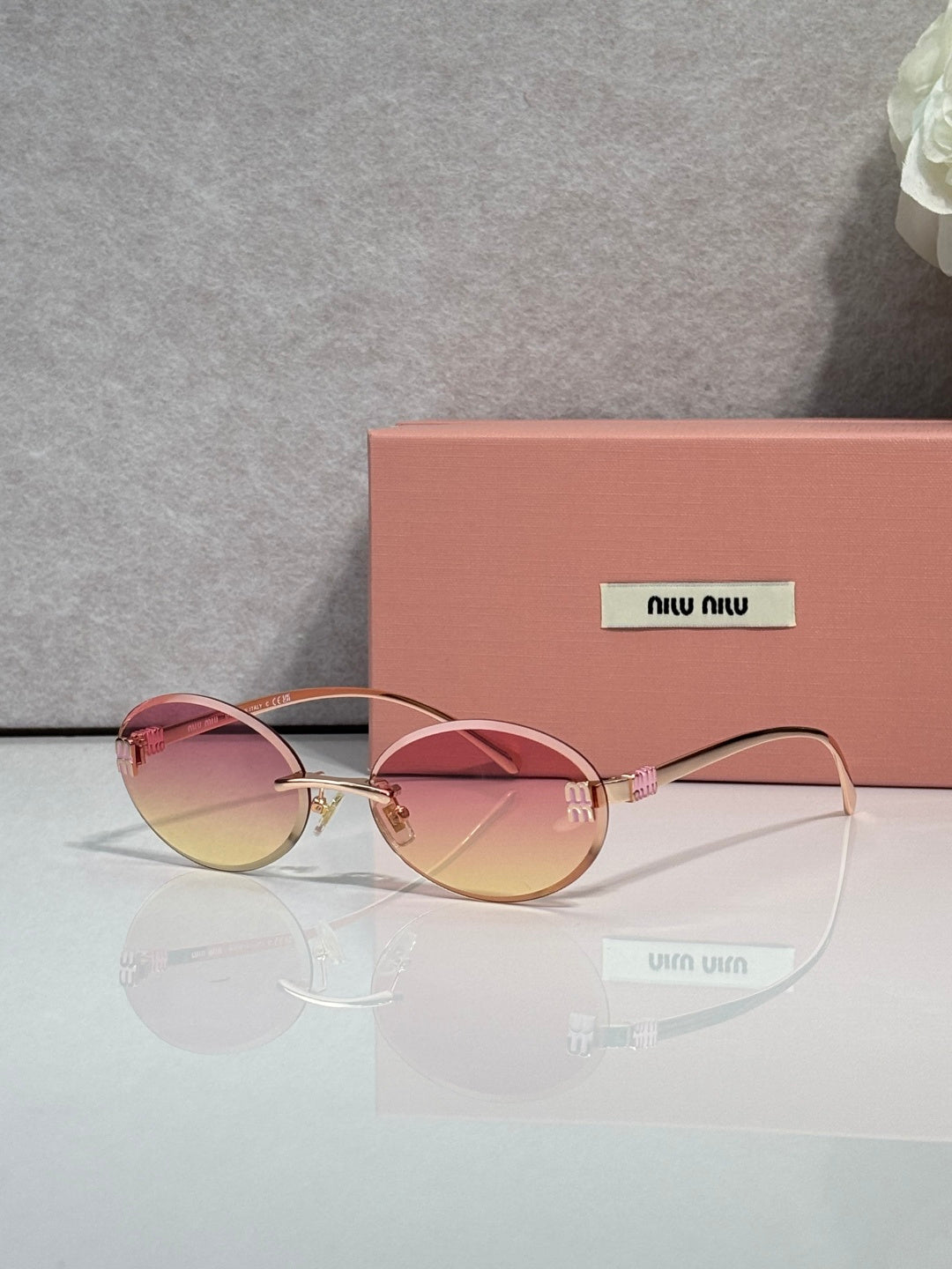 MiuMiu round sunglasses with pink lenses, gold-toned metal frame, logo on temples