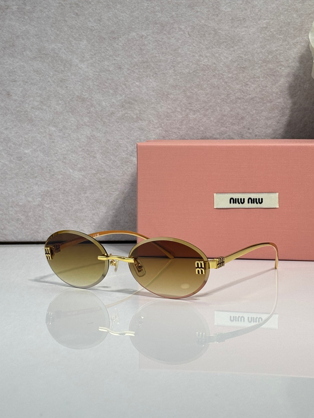 MiuMiu round sunglasses with olive lenses, gold-tone metal frame, logo details on temples