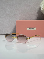 MiuMiu round sunglasses with light tinted lenses, gold-toned frame, logo on temples
