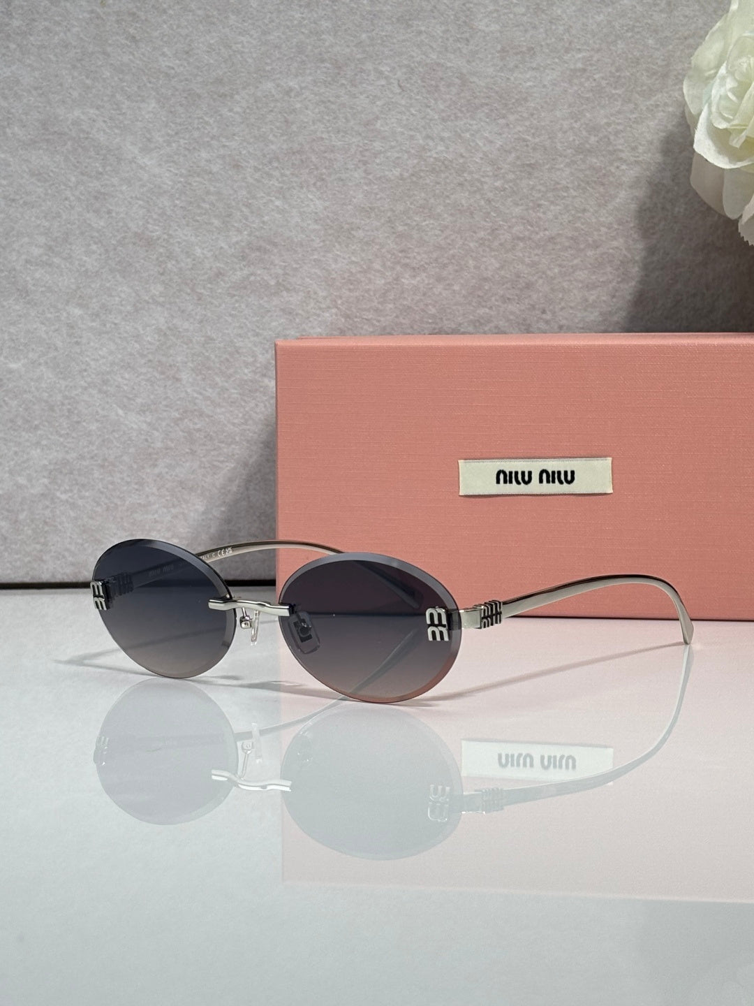 MiuMiu round sunglasses with dark lenses, gold-toned metal frame, logo on temples