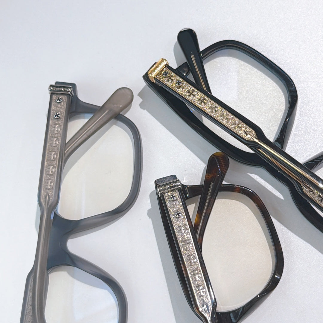 Two eyeglass frames laid flat: dark black-gold and gray with clear lenses