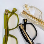 Set of eyeglasses with green, clear, and black frames with gold-tone details