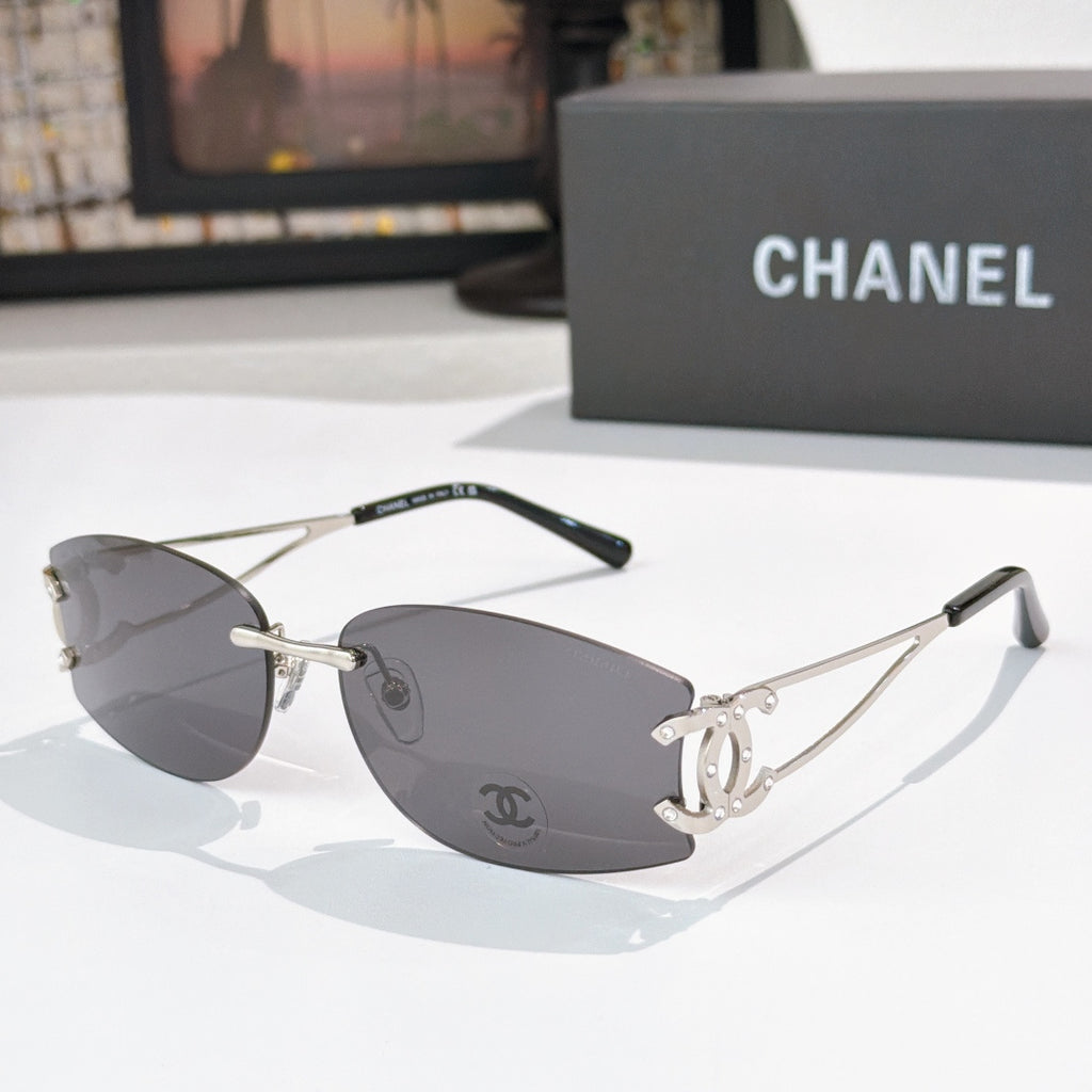Silver aviator sunglasses with dark gray lenses and Chanel logo at the temple