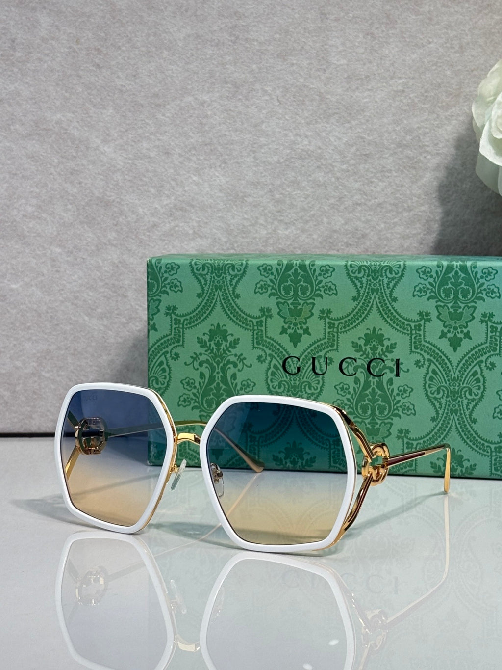 Sunglasses with white square frames and blue tinted lenses, gold-tone hinges